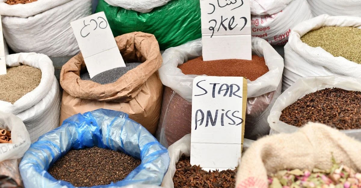 Une sélection vibrante d'épices dans un marché animé avec des sacs étiquetés d'anis étoilé.