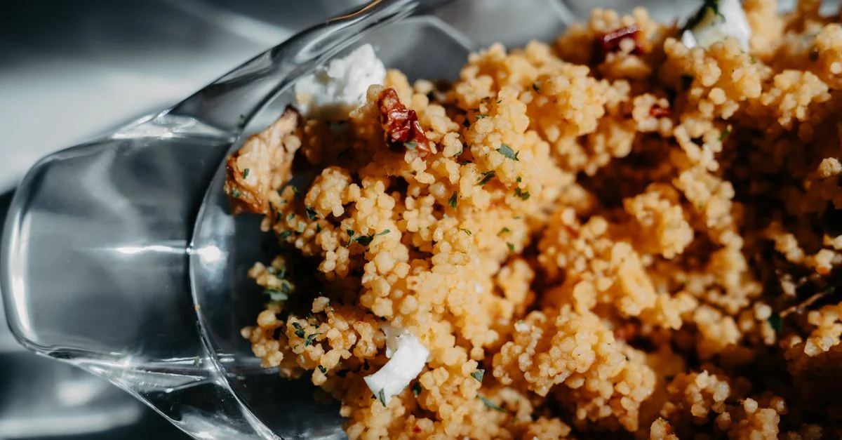 Gros plan sur un délicieux plat de couscous fait maison servi dans un bol transparent, mettant en valeur sa texture.