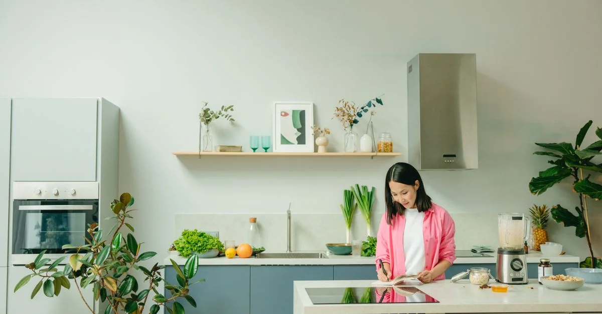 Femme asiatique coupant des légumes sur un plan de travail de cuisine dans un cadre moderne et élégant.
